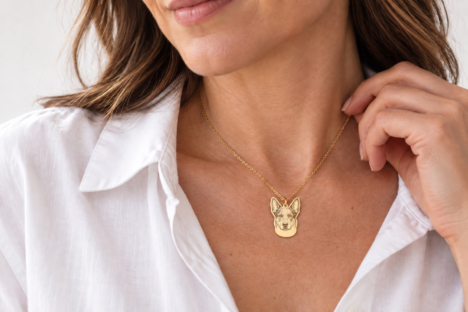 A personalized pet portrait necklace worn with a white shirt